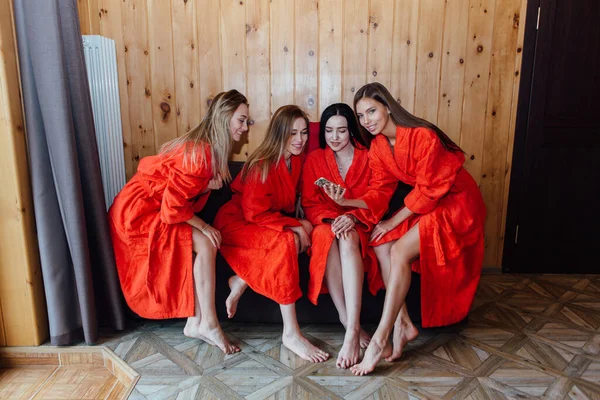 Four Beautiful Young Women Dressed Red Bathrobe Sitting Couch Smiling — Stock Photo, Image