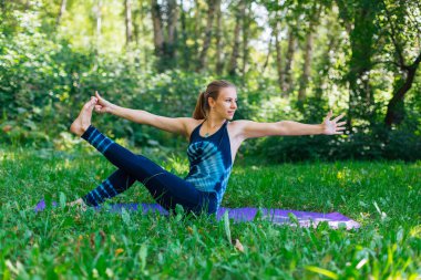 Beyaz bir kadın yaz kenti parkında yoga egzersizleri yapıyor..