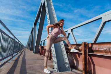 Gün batımında nehrin üzerindeki eski paslı nakliye köprüsünde poz veren genç ve güzel bir kadının ılık yaz portresi..