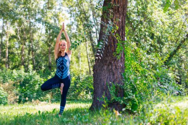 Beyaz bir kadın yaz kenti parkında yoga egzersizleri yapıyor..