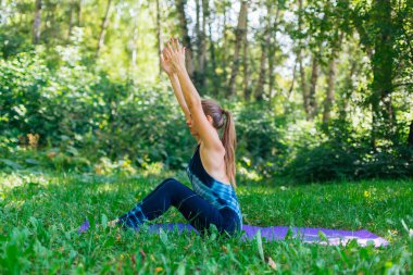 Beyaz bir kadın yaz kenti parkında yoga egzersizleri yapıyor..