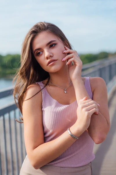 Mujer joven y bonita posando en el viejo puente de transporte oxidado sobre el río durante el atardecer . — Foto de Stock