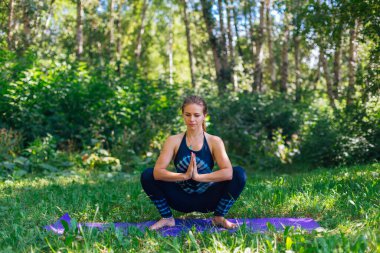 Beyaz bir kadın yaz kenti parkında yoga egzersizleri yapıyor..