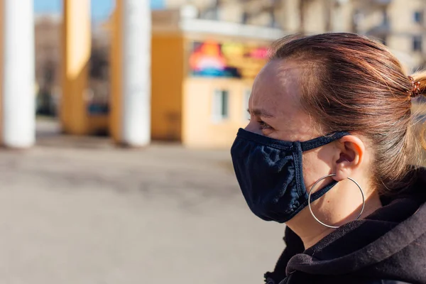 Caucasian woman wearing black fabric face mask. Concept of using medical mask to prevent the spread of germs, such as Coronavirus COVID-19.