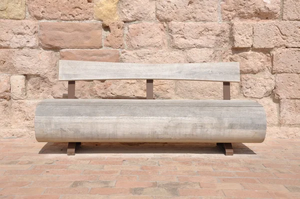 Banco de madera contra una pared de piedra — Foto de Stock