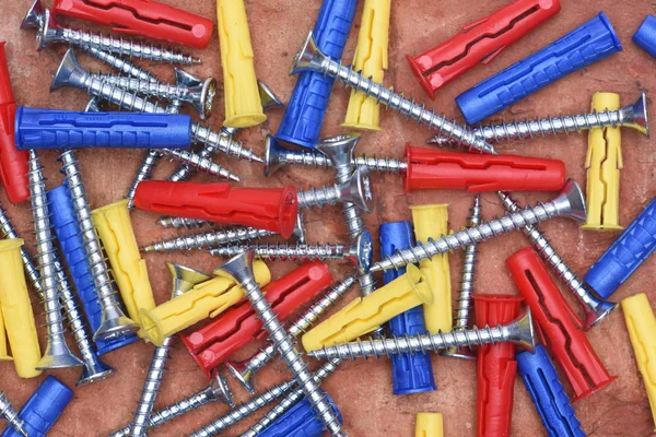 Tornillos de plástico y tornillos sobre fondo de ladrillo rojo — Foto de Stock