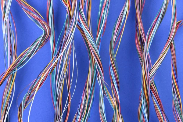 Swirl of colorful electric cables on blue background