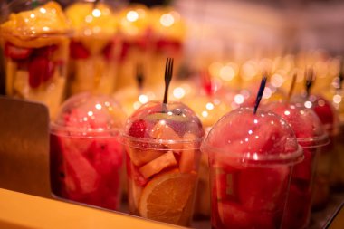 Yakın çekim sokak pazarında plastik bardakta taze meyve dilimlenmiş.