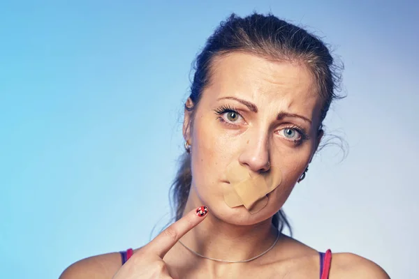Jonge vrouw met zijn mond gelijmd met tape. — Stockfoto