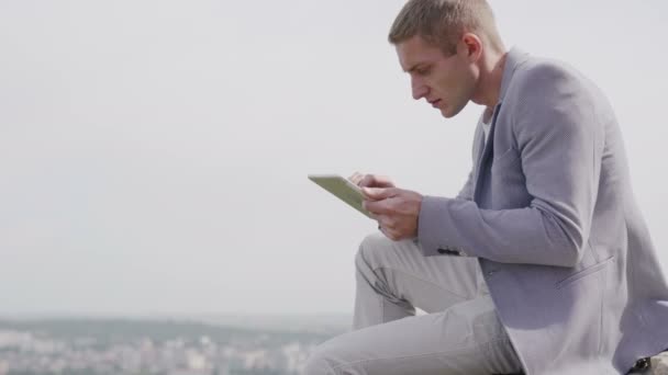 Homem trabalhando em tablet ao ar livre, ele está satisfeito com seu trabalho — Vídeo de Stock