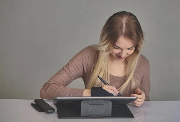 Artista chica dibuja un bolígrafo digital en una tableta profesional en su estudio —  Fotos de Stock