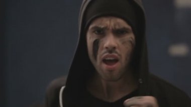 Spor kıyafetleri içindeki kaslı genç adam tekme atıyor.