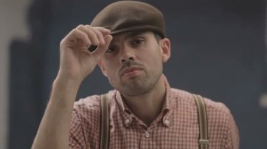 Pantolon askılı ve şapkalı bir adam.