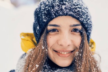 Kış portresi, örgü örülmüş, karla kaplı bir züppe giyen güzel bir kadın. Kar yağan kış güzellik moda konsepti