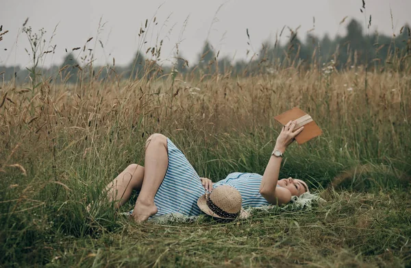 Woman lying on plaid in field and enjoying reading books. — Stock Photo, Image