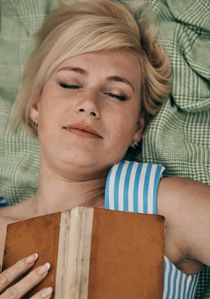 Nő feküdt kockás területen, és élvezi az olvasás könyveket. — Stock Fotó