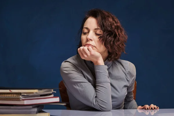 Vrouw kijkt naar stapel papieren aan haar bureau zonder verlangen om te werken — Stockfoto