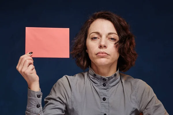 Depressed woman shows us a pink envelope — Stok fotoğraf