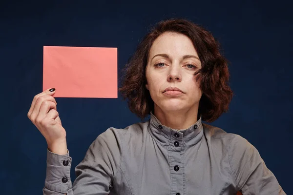 Mulher deprimida nos mostra um envelope rosa — Fotografia de Stock