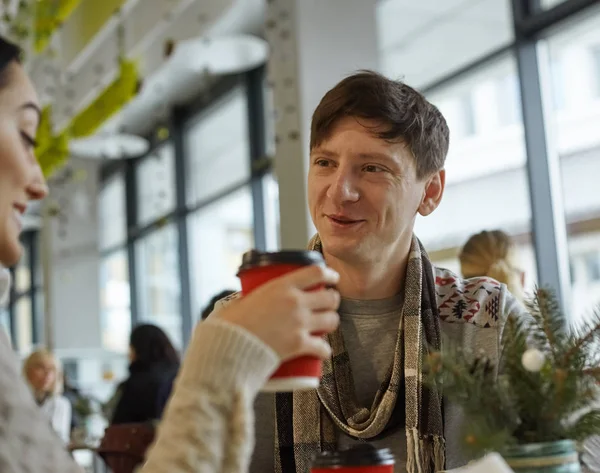 Smiling young man talking to a woman in a cafe — ストック写真