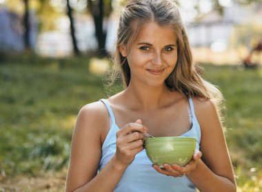 Portrait of happy smiling young woman eating noodles
