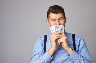 man sniffs money in his hands