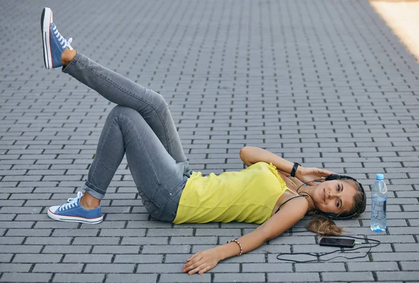 Mädchen liegt im Sommer auf dem Gehweg und hört leise Musik — Stockfoto