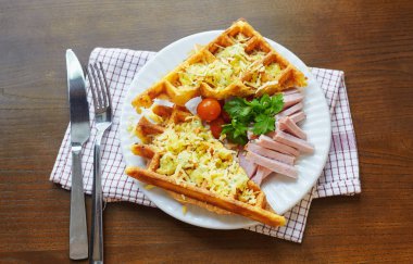 Etli peynirle kaplı bir waffle, tabakta maydanoz yaprakları
