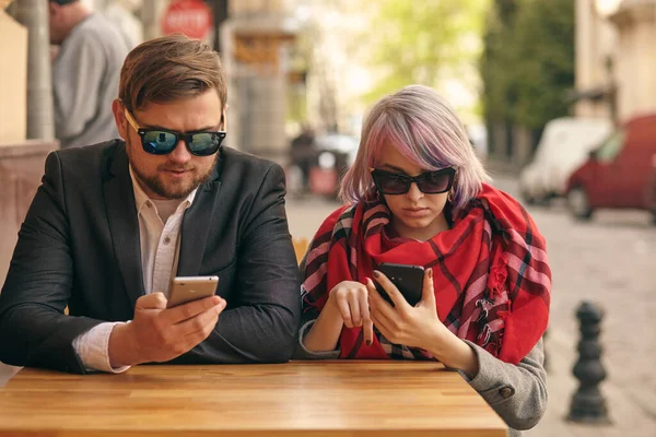 Bild av ett glädjefyllt par som använder smartphones i staden — Stockfoto