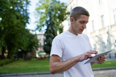 Şehrin ortasında yaratıcı bir adam ve bir tablet bilgisayar kullanıyor.
