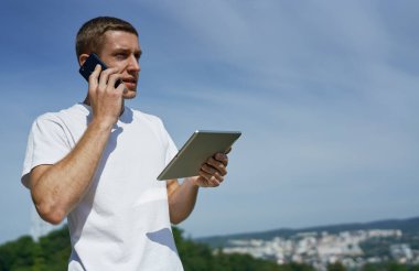 Adam çalışırken dışarıda dijital tablet tutuyor.