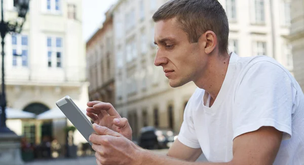 Kreativní muž sedí na chodníku a pomocí tabletu počítače — Stock fotografie