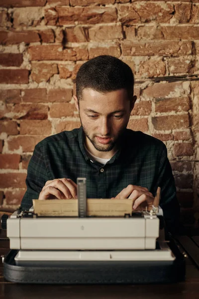 Jongeman schrijft op oude typemachine. — Stockfoto