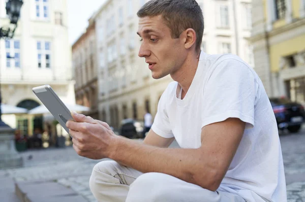 坐在人行道上的男人用平板电脑 — 图库照片