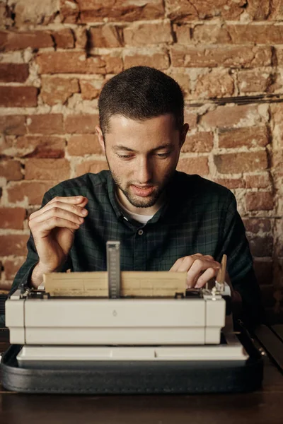 Egy fiatal író, aki egy klasszikus írógépen dolgozik. Boldog és nem siet. — Stock Fotó