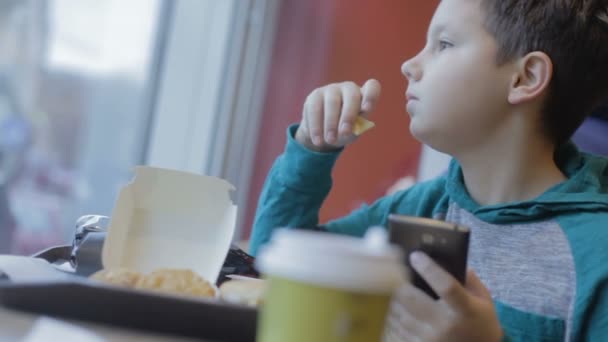 Hongerige tiener eet junkfood. Een close-up. Burger, cheeseburger, broodje — Stockvideo