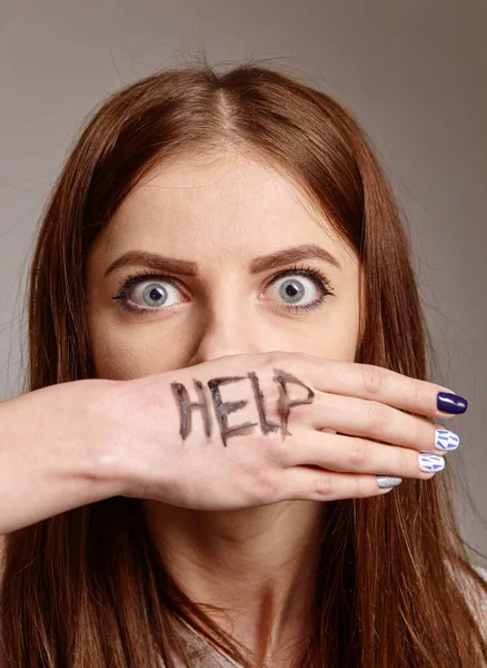 Verängstigtes weibliches Gesicht bedeckt mit einer Hand mit der Aufschrift Hilfe. — Stockfoto