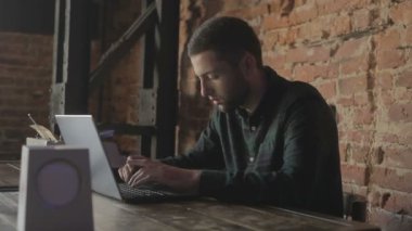 İşadamı odaklı girişimci dizüstü bilgisayarla araştırma yapıyor. Bilgisayarı kullanan genç profesyonel bir erkek ofis masasında oturuyor. Modern teknoloji not defteri üzerinde çalışan meşgul bir işçi..