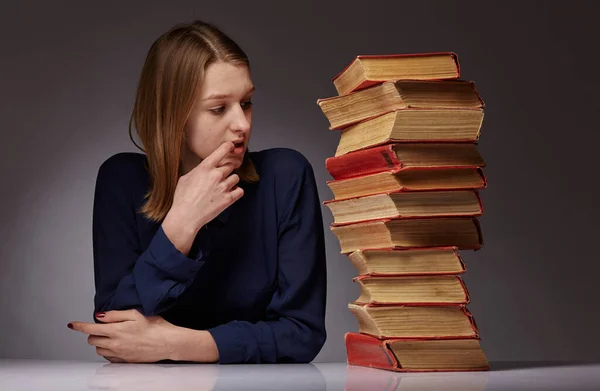 Chica joven y un montón de libros a su lado. ella tiene dificultades para aprender . —  Fotos de Stock