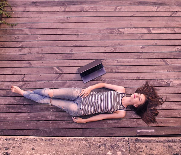 Jong aantrekkelijk meisje ontspannen op een houten vloer. Ontspan, rust, onderwijsconcept, recreatie . — Stockfoto