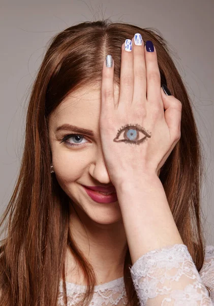 Staring brunette woman with painted eyes on her hand as a symbol of not fair play and double standards gestures, body language, psychology concept — Stock Photo, Image