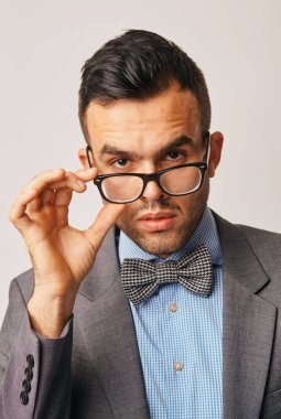 Gözlüklü adam gözlerini kaçırıyor ve gri duvara yaslanıyor. Gözlüklü genç işadamının portresi. Fotokopi alanı olan kariyerini düşünüyor.