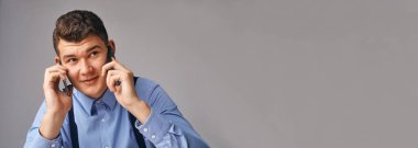 Gömlekli yakışıklı işadamı ofiste telefonla konuşuyor..