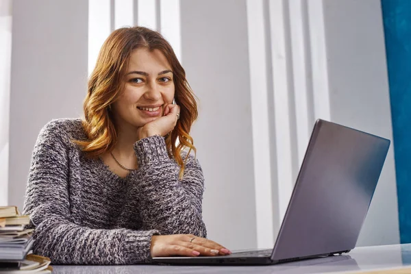 Retrato de una feliz mujer de negocios casual en suéter sentada en su lugar de trabajo en la oficina —  Fotos de Stock