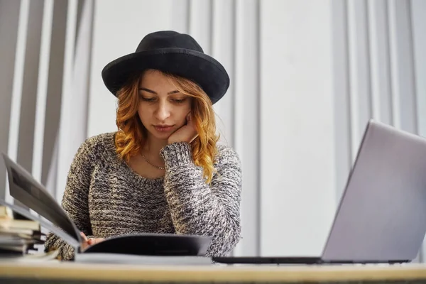 Retrato de una feliz mujer de negocios casual en suéter sentada en su lugar de trabajo en la oficina. Ella está revisando el documento —  Fotos de Stock