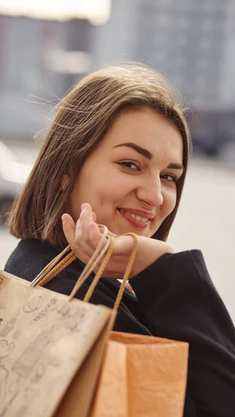 Şehirde alışveriş torbalarıyla gülümseyen bir kız. — Stok fotoğraf