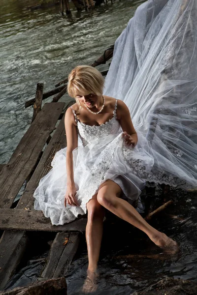 滝のそばの白いウェディング ドレスの若いブロンドの女性 — ストック写真