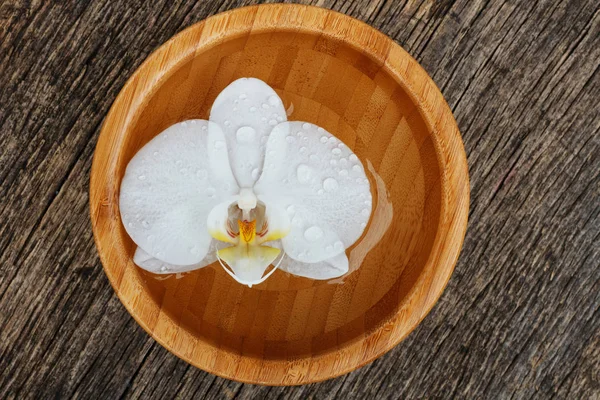 Orquídea blanca, flor phalaenopsis en tazón de bambú en respaldo de madera —  Fotos de Stock