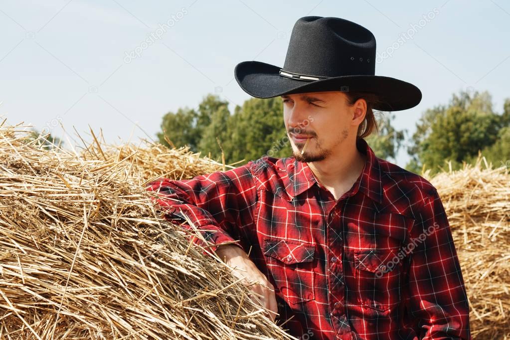 young cowboy near a haystack