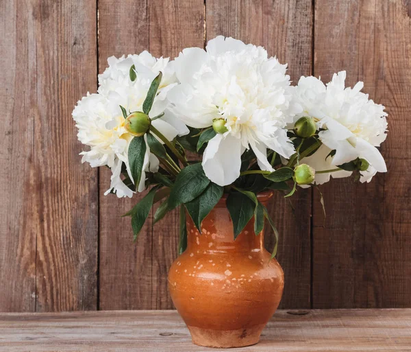Bouquet di peonie bianche in brocca di argilla su fondo rustico in legno — Foto Stock